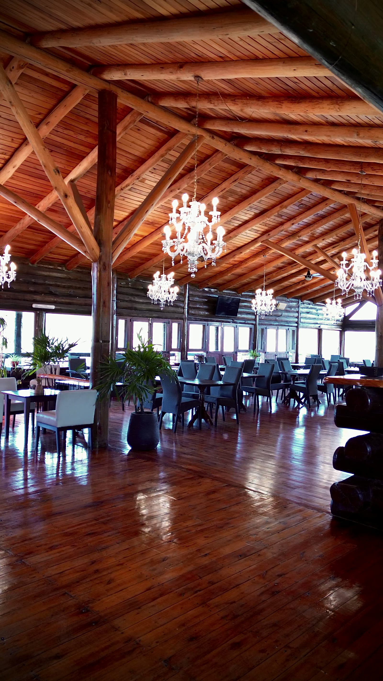 El salón a lo largo, con el techo de madera y las arañas encendidas